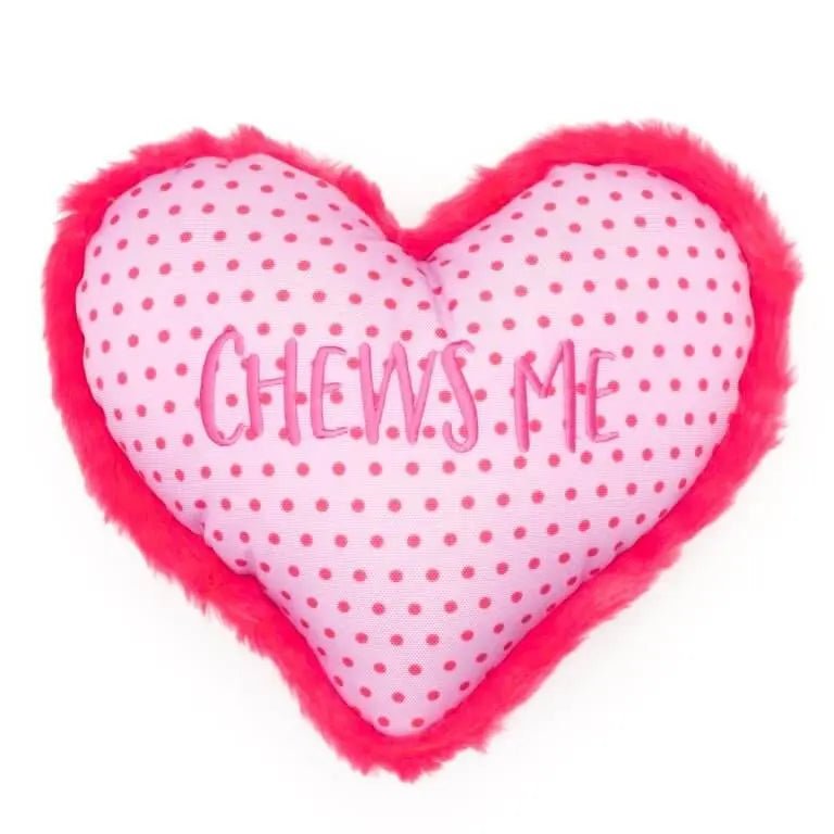 Różowa pluszowa zabawka w kształcie serca z napisem "CHEWS ME", idealna dla psów do gryzienia i aportowania. Polka dot wzór, czerwona futrzana krawędź.